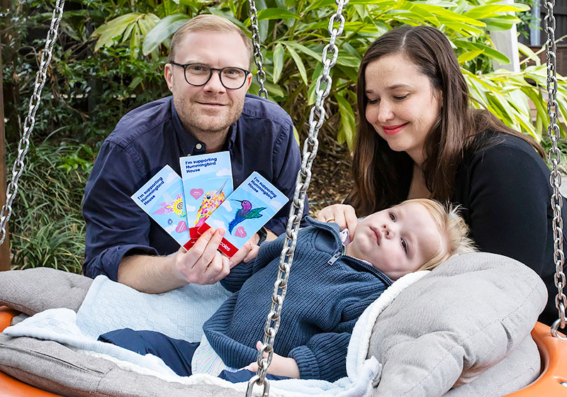 Hummingbird House mum, dad and child holding the three $2 donation cards